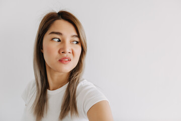 Asian women take selfie with dislike hate face isolated white wall look at empty space.