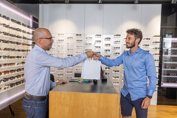 Man buying glasses in eyewear store