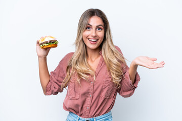 Young pretty Uruguayan woman holding a burger isolated on white background with shocked facial expression