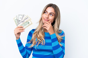 Young Uruguayan woman taking a lot of money isolated on white background having doubts