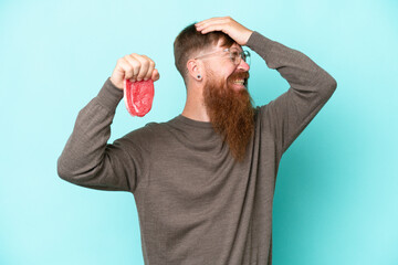 Redhead man with long beard holding a piece of meat isolated on blue background has realized something and intending the solution