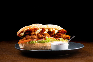 large sub sandwich of pork or fried chicken breaded with lettuce tomato and mayonnaise barbecue...