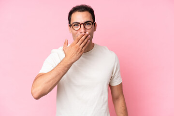 Young caucasian man isolated on pink background happy and smiling covering mouth with hand
