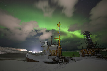 Famous abandoned ship at Barents sea coast under Northern lights sky