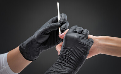 A manicurist removes cuticles during a nail extension procedure in a beauty salon. Professional hand care.