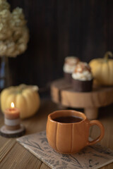 A cozy still life with a cup in the form of a pumpkin, a candle and small pumpkins