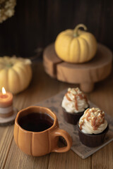 A cozy still life with a cup in the form of a pumpkin, a candle and small pumpkins