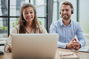 smilling man and charming woman are sitting at laptops in headphones
