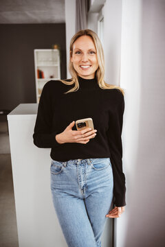 Young Woman Laughing at Camera with Smartphone in Hand