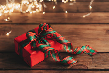 Gift boxes with a large red bow against a background bokeh of twinkling party lights. Luxury New...