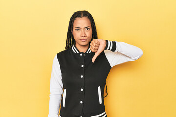Indonesian woman in classic black baseball jacket showing a dislike gesture, thumbs down....