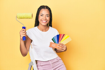 Indonesian woman with ladder, roller, color palette on yellow