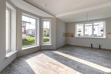 A room in a private house immediately after laying the floor, white unfinished walls and ceiling