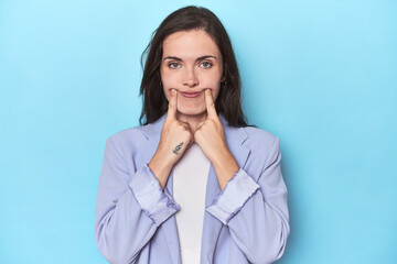 Woman in blue blazer on blue background doubting between two options.