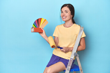 Woman with color palette painting wall on ladder