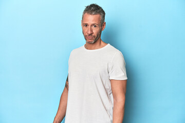 Fototapeta premium Middle-aged man posing on blue studio backdrop