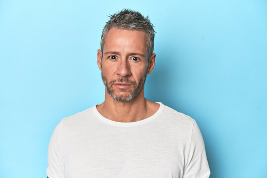 Middle-aged man posing on blue studio backdrop