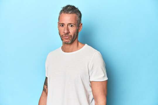 Middle-aged man posing on blue studio backdrop