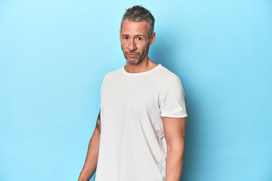Middle-aged man posing on blue studio backdrop