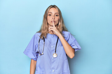 Young caucasian nurse in blue studio keeping a secret or asking for silence.