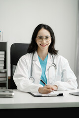 Female doctor sitting at a desk, looking at the camera.