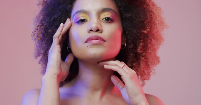 Biracial woman with dark curly hair in blue and pink light, slow motion