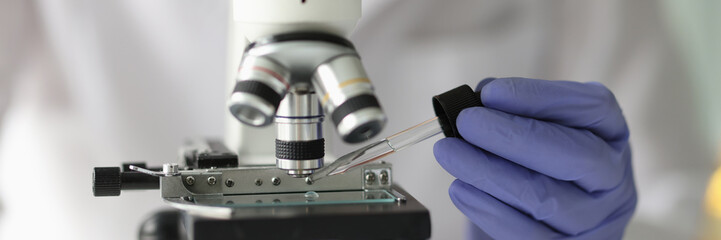 Chemist lab assistant looking at test sample using microscope