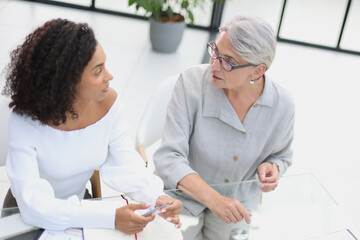 Female colleagues met in the office hall discussing work issues