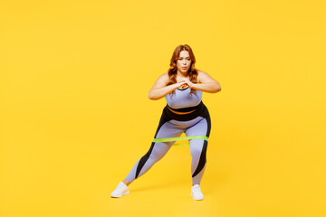 Fototapeta na wymiar Full body young chubby plus size big fat fit woman wear blue top warm up train use rubber elastic bands for legs do squats isolated on plain yellow background studio home gym. Workout sport concept.