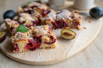 Rustic plum crumble cake sliced on a wooden cutting board