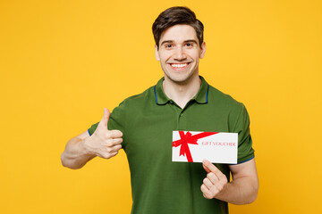 Young smiling happy man he wears green t-shirt casual clothes hold gift certificate coupon voucher...