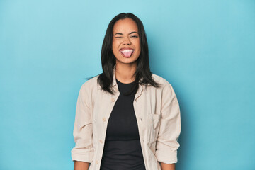 Obraz premium Filipina young woman on blue studio funny and friendly sticking out tongue.