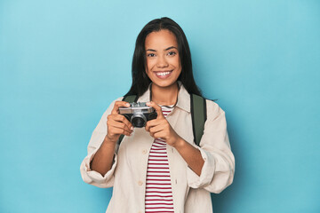 Young Filipina capturing moments with camera on a blue studio backdrop