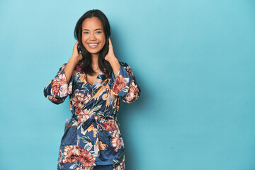 Joyful Filipina in traditional kimono posing on blue studio backdrop