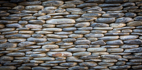 Grey river pebbles round stone wall background