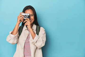 Young Filipina capturing moments with camera on a blue studio backdrop