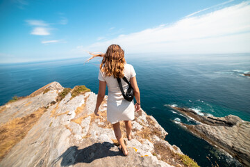 Seeking serenity: Woman strolls to the rocky cliff's edge, embracing tranquility on a paradise...