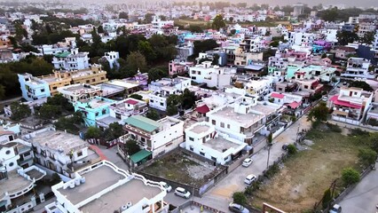 Aerial view of Dehradun city in India with valley view of houses and mountains during orange sky sunrise.Cinematic pullback drone shot of beautiful landscape at sunrise with sunrise at mountain top 