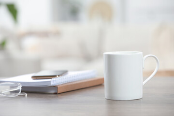 White ceramic mug and notebooks on wooden table indoors. Space for text