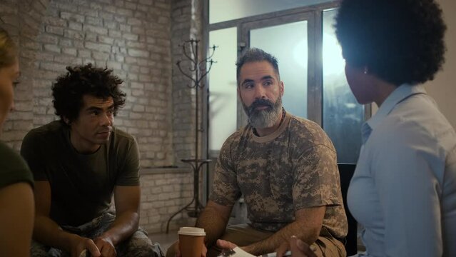 Group of diverse veterans talking during PTSD support group. - Powered by Adobe