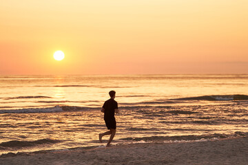 Silhouette of a Sportsman Running at Ocean Sunset. One person running against the sun.
