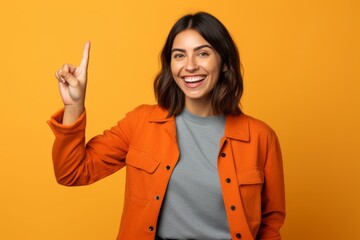 Medium shot portrait photography of a happy girl in her 30s making an ok gesture with the fingers against a bright orange background. With generative AI technology