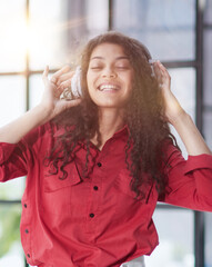 Beautiful smiling young woman in headphones in modern office