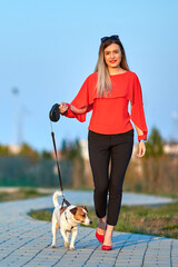 Beautiful girl with her friend Jack Russell dog walking in the park.