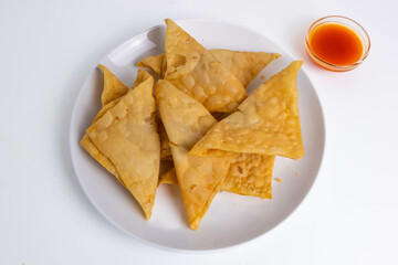 Pangsit, Pangsit Goreng, Delicious Pangsit Ayam Goreng (Chicken Fried Dumpling), Indonesian Traditional Food made from flour and chicken. Served in white plate with sauce.