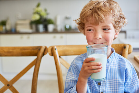 Smiling boy holding glass of milk at home