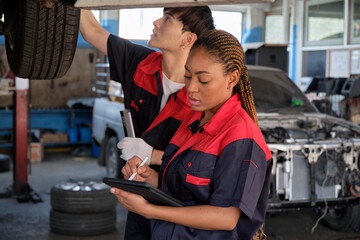 Young expert Black female inspects repair checklist with automotive mechanic worker partner, quality suspension technician team at fix garage. Vehicle maintenance service works industry occupation job