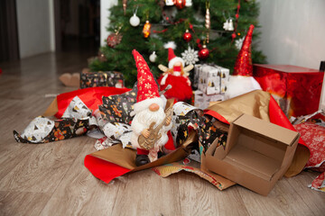 gnomes and angels under the Christmas tree among torn wrapping paper, a mess under the tree after...
