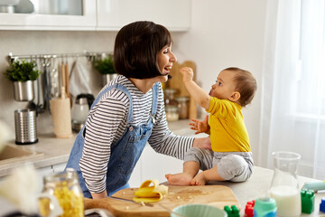 Baby boy feeding his mother in the kitchen