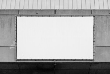 Big screen or white canvas on a concete facade of modern building. Geometrical perspective with of rectangular streched field used for advertising or beamer projections. Black and white background.